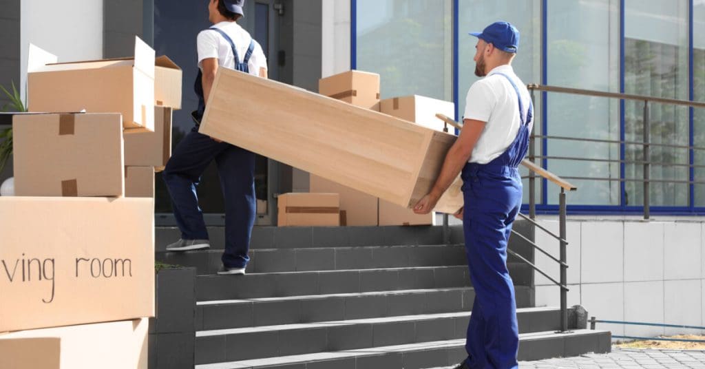 Male movers carrying shelving unit into new house